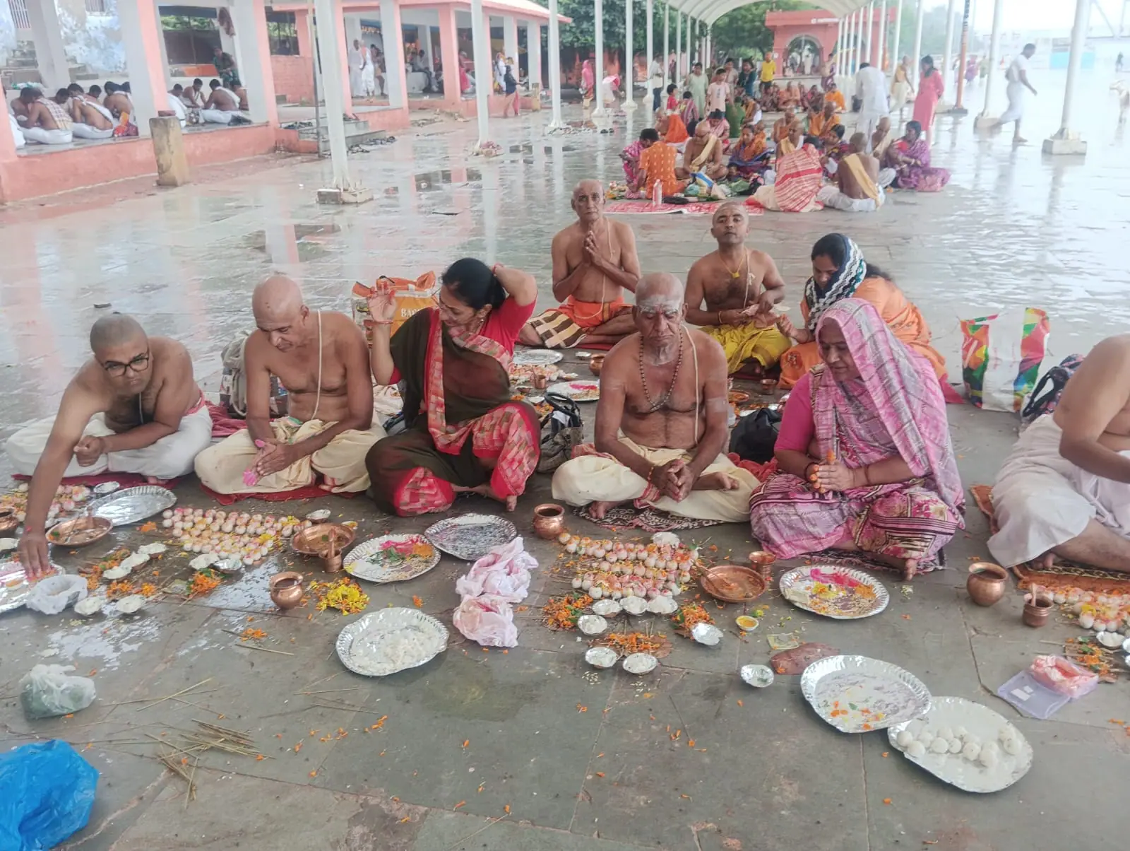 Families seated on the floor of a covered ritual hall at Bindu Sarovar, offering rice pindas on leaf plates